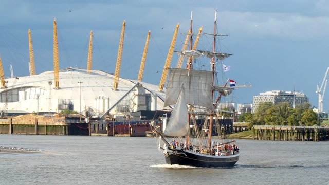 Historic tall sailing ship on the river Thames at Greenwich, with the Millennium dome in the background