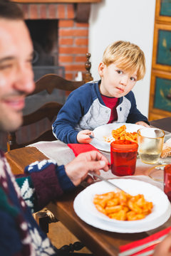 Playful Dad Feeding Kid with Pasta at Christmas Dinner