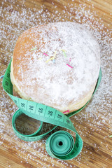 closeup of a tape measure and donut with powdered sugar