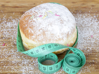closeup of a tape measure and donut with powdered sugar