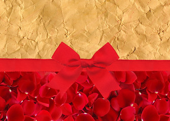beautiful red rose petals and red ribbon with bow over yellow ol