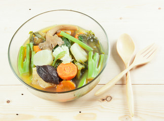 Fresh hot vegetable soup and spoon on wood