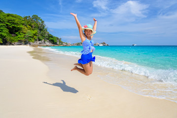 Fototapeta na wymiar Tourist girl in a blue white striped swimsuit jumping with happy on the beautiful beach and sea during summer at Koh Miang Island, Mu Ko Similan National Park, Phang Nga province, Thailand