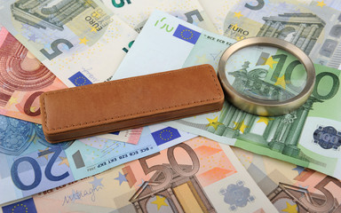 Magnifying glass lying on Euro banknotes
