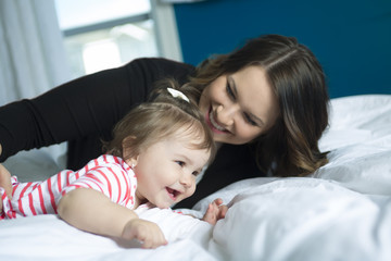 Mother and baby playing and smiling on the bedroom