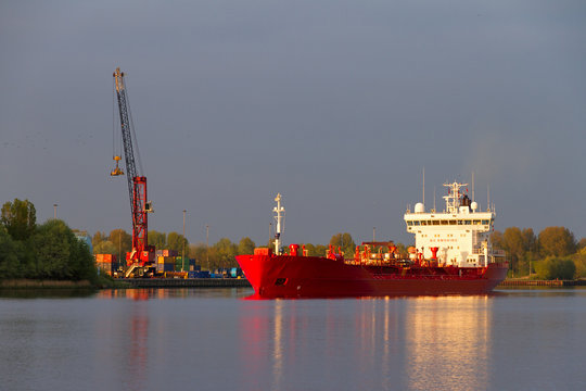 Big red cargo ship in the waters of IJmuiden, the Netherlands, heading for the ocean at sunset