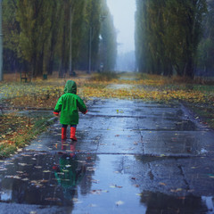 Toddler running in autumn rainy park