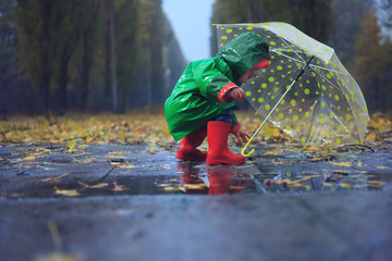 Toddler and umbrella in autumn rainy park