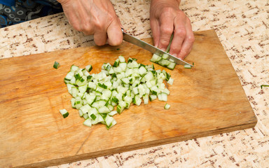 The chef cuts the cucumber on a wooden  Board.