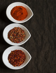 assorted spices in white bowls on a dark wooden surface