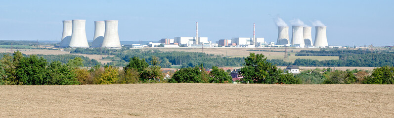nuclear power plant against the blue sky, trees and field