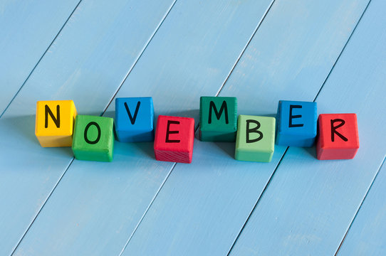 Word November On child's toy cubes on wooden rural  background.