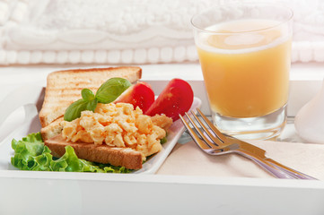 Breakfast on a wooden tray eggs scrambled and juice