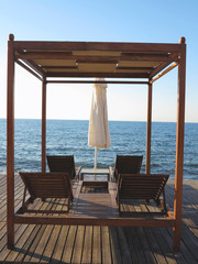 Fototapeta na wymiar Beach chairs and umbrella on the sand near sea, blue sky