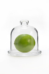 Green lemon in a glass flask on a white background