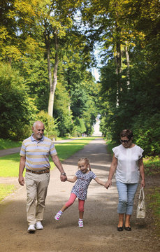 Grandparents With Grandchild walking together in the park