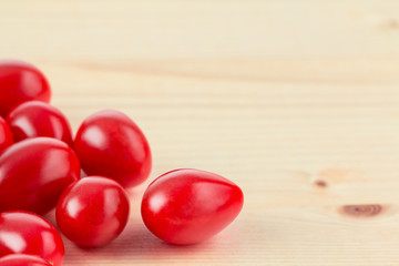 Ripe red grape tomatoes on wood grain background