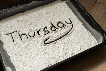 Thursday Word Written on Baking Sheet Covered with White Flour