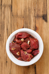 marinated meat in white plate on wooden background