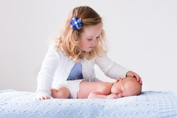 Little girl playing with newborn baby brother