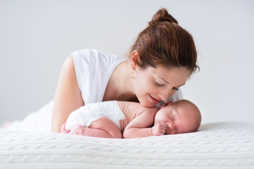 Young mother and newborn baby in white bedroom