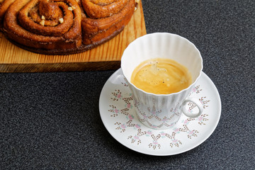 Cup of coffee and cinnamon bun with caramel syrup