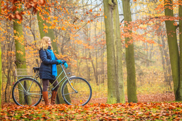 Active woman riding bike in autumn park.