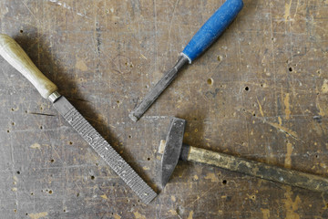Old carpenters hammer rasp and chisel on vintage wooden backgrou