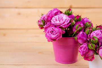 Pink roses in a vase on wooden background