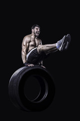 Fototapeta na wymiar Sportsman exercising on a tire isolated