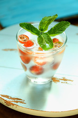 Glass of cold refreshing summer drink with berries and ice cubes on table close up