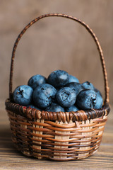 Fototapeta na wymiar Tasty ripe blueberries in basket on wooden table close up