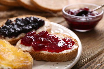 Fresh toast with butter and different jams on table close up