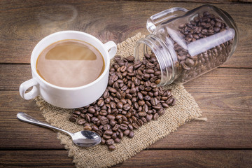 Coffee cup and beans on a wooden table.
