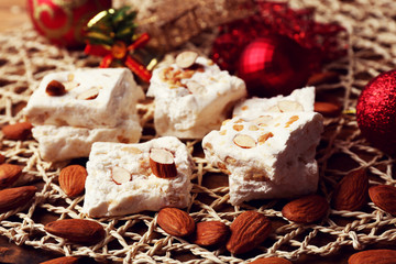 Sweet nougat with almonds and Christmas decoration table close up