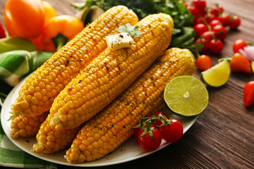 Appetizing grilled corn served with vegetables and green plaid pattern napkin