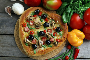 Delicious heart shaped pizza with vegetables on wooden background, close up