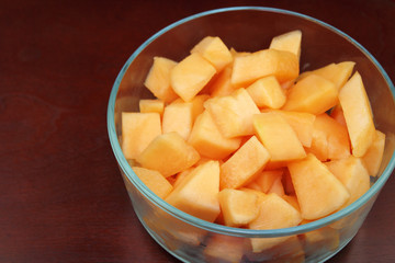 Cantaloupe Pieces in a Clear Glass Bowl on Wood