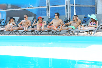 Young people relaxing on chaise-lounges