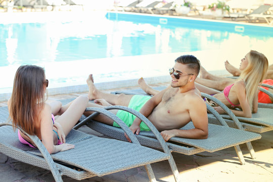 Young people relaxing on chaise-lounges