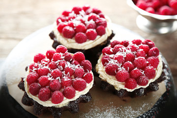 Sweet cakes with raspberries on wooden table background