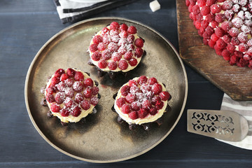 Sweet cake with raspberries on color wooden background