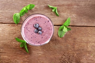 Fresh blueberry yogurt decorated with berries and mint on wooden background