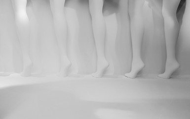 Row of mannequin legs against white background in store display window