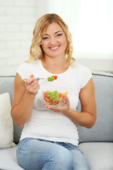 Obraz na płótnie Canvas Beautiful woman with salad on home interior background