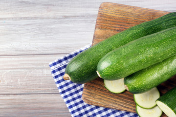 Fresh sliced zucchini on cutting board, on wooden background