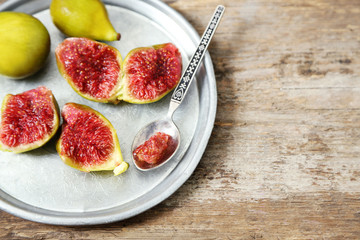 Ripe figs on tray, on wooden background