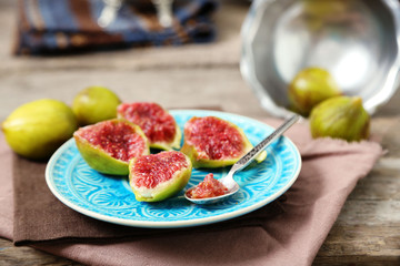 Ripe figs on plate, on wooden background