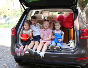 Happy children sitting on a car trunk