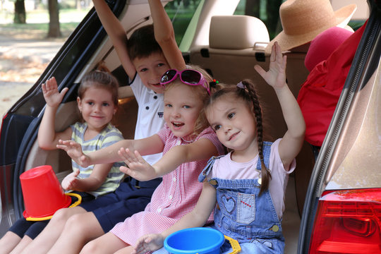 Happy children sitting on a car trunk